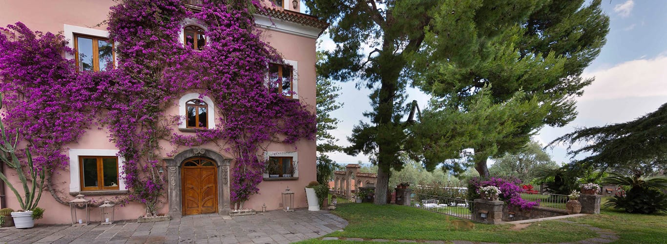 Edificio presso Capo Santa Fortunata con pareti rosa e una pianta viola.