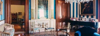 Sala della Casa Dentice con mobili vintage e pareti con tappezzeria a righe.